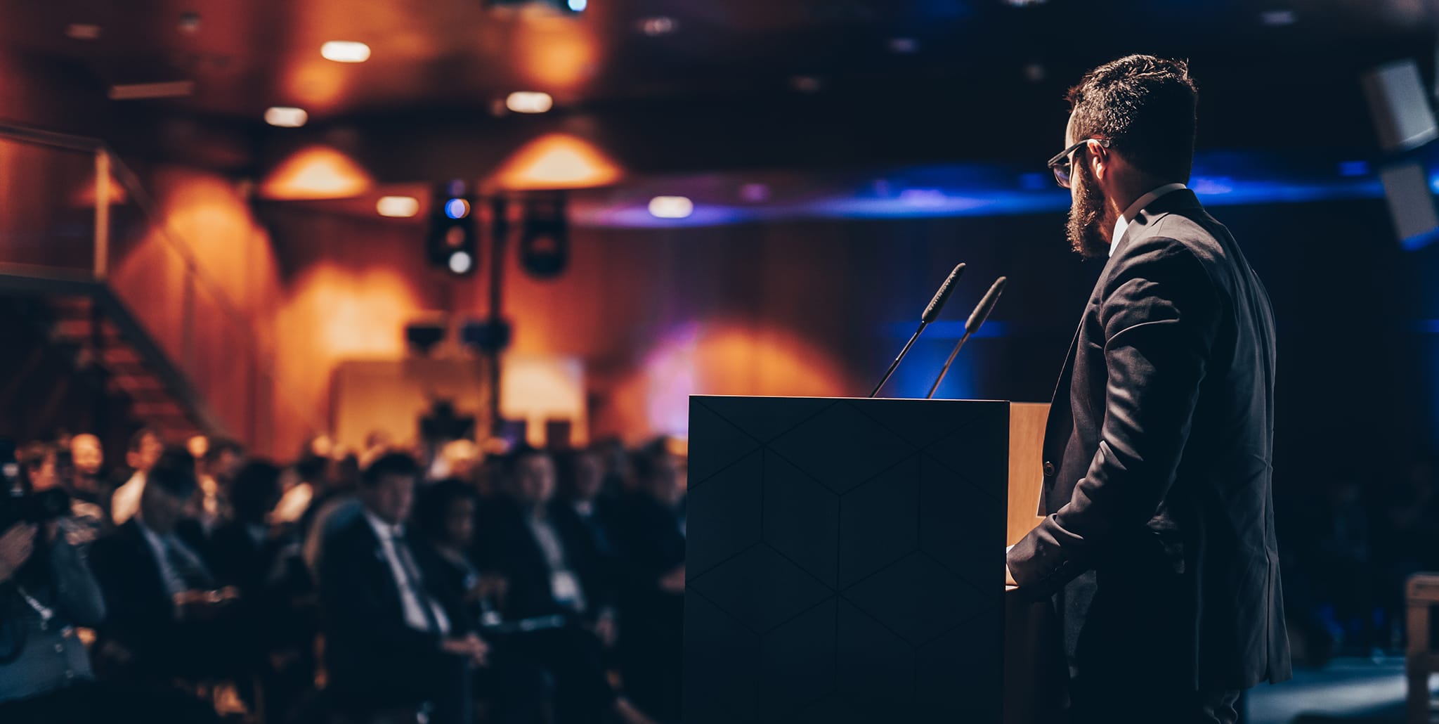 Corporate events speaker presenting to a business audience during a professional conference experience.