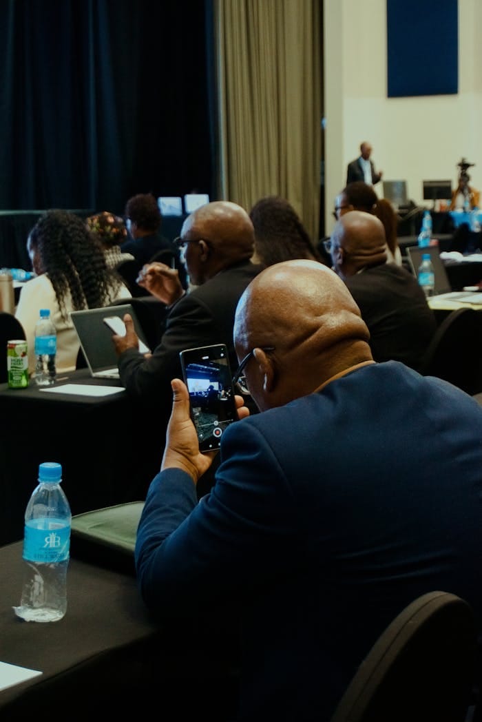 Attendees at a business conference capturing moments on phones for notes and sharing.