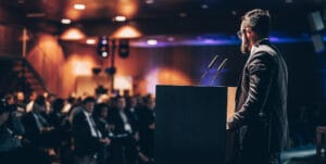 Speaker presenting to an audience during a conference about event psychology and memorable event experiences